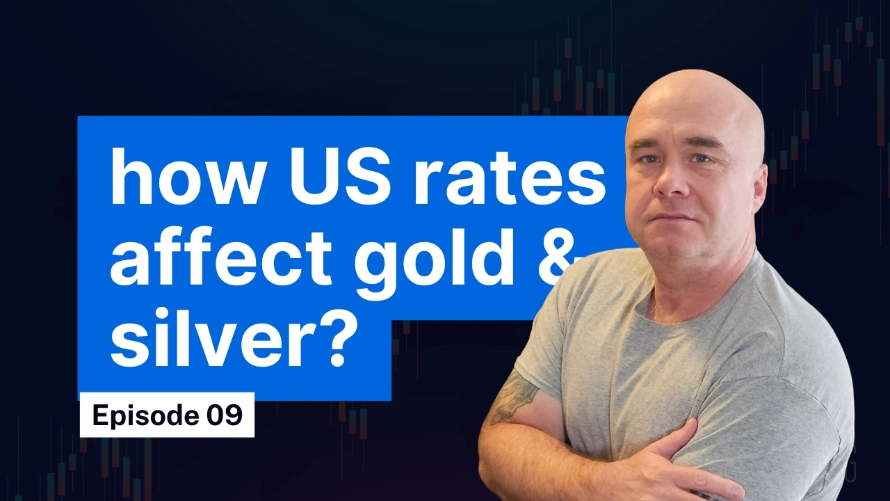 Man in grey shirt with folded arms beside bold text "how US rates affect gold and silver" in episode 9 with a candlestick chart background.