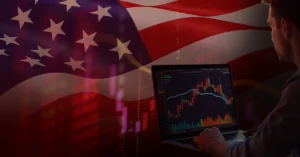 Man viewing a stock chart with red and green candlesticks on a laptop, overlaid with a U.S. flag.