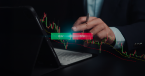 A person using a stylus on a tablet with price candlestick charts and glowing buy and sell buttons displayed on the screen